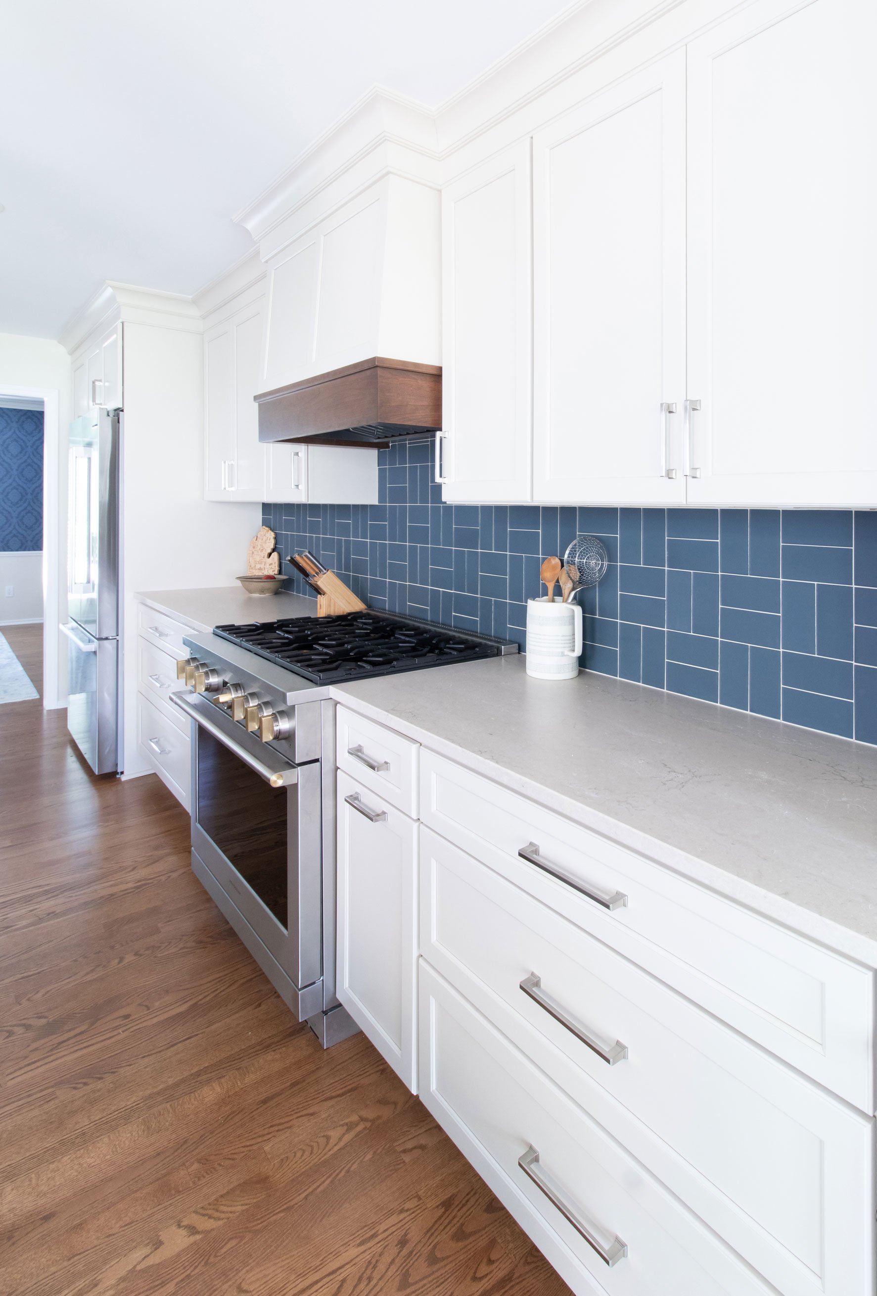 Off-white kitchen cabinetry with professional-style range and wood hood.