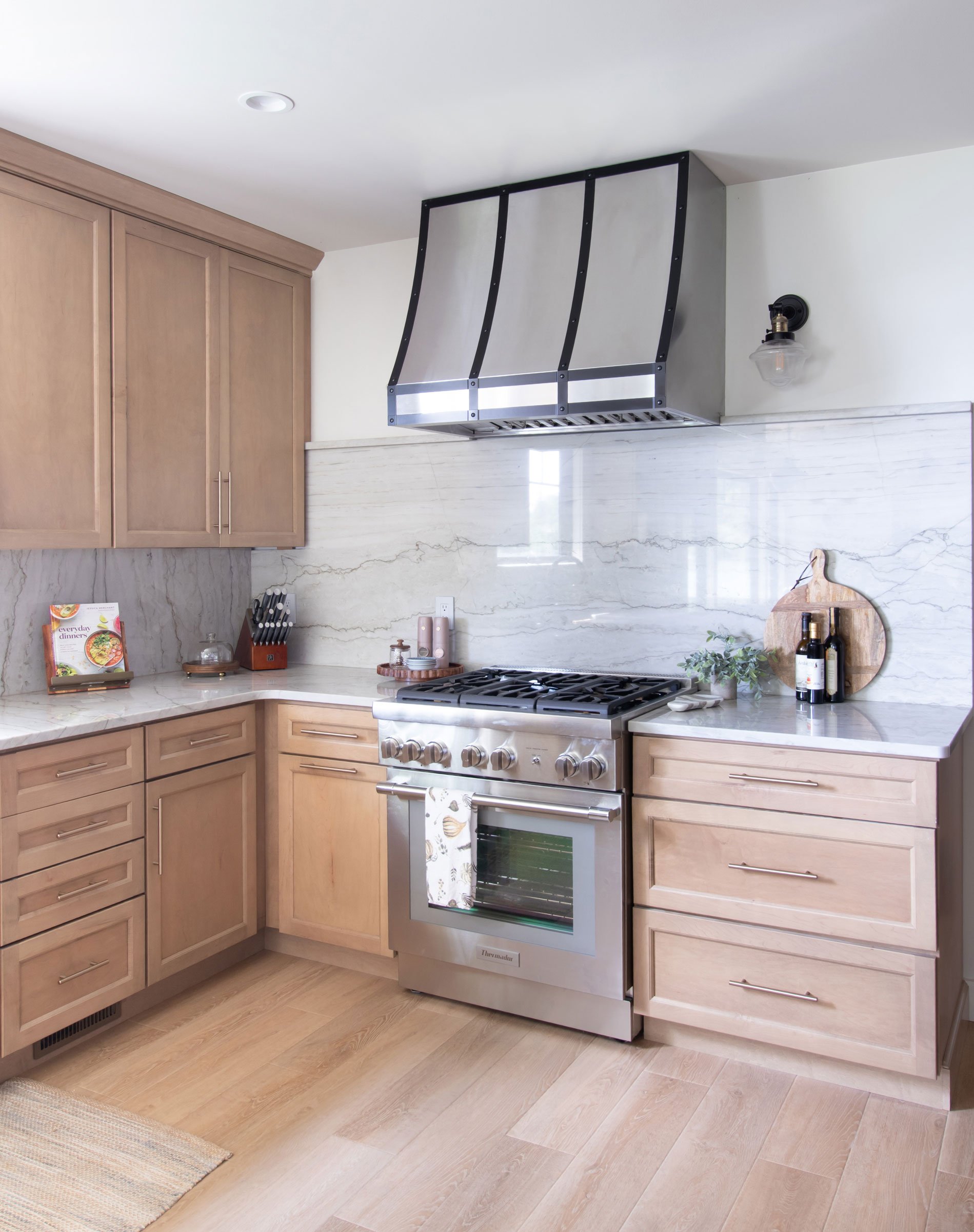 Close-up of range wall with hood, marble-look backsplash, and cutting board display.