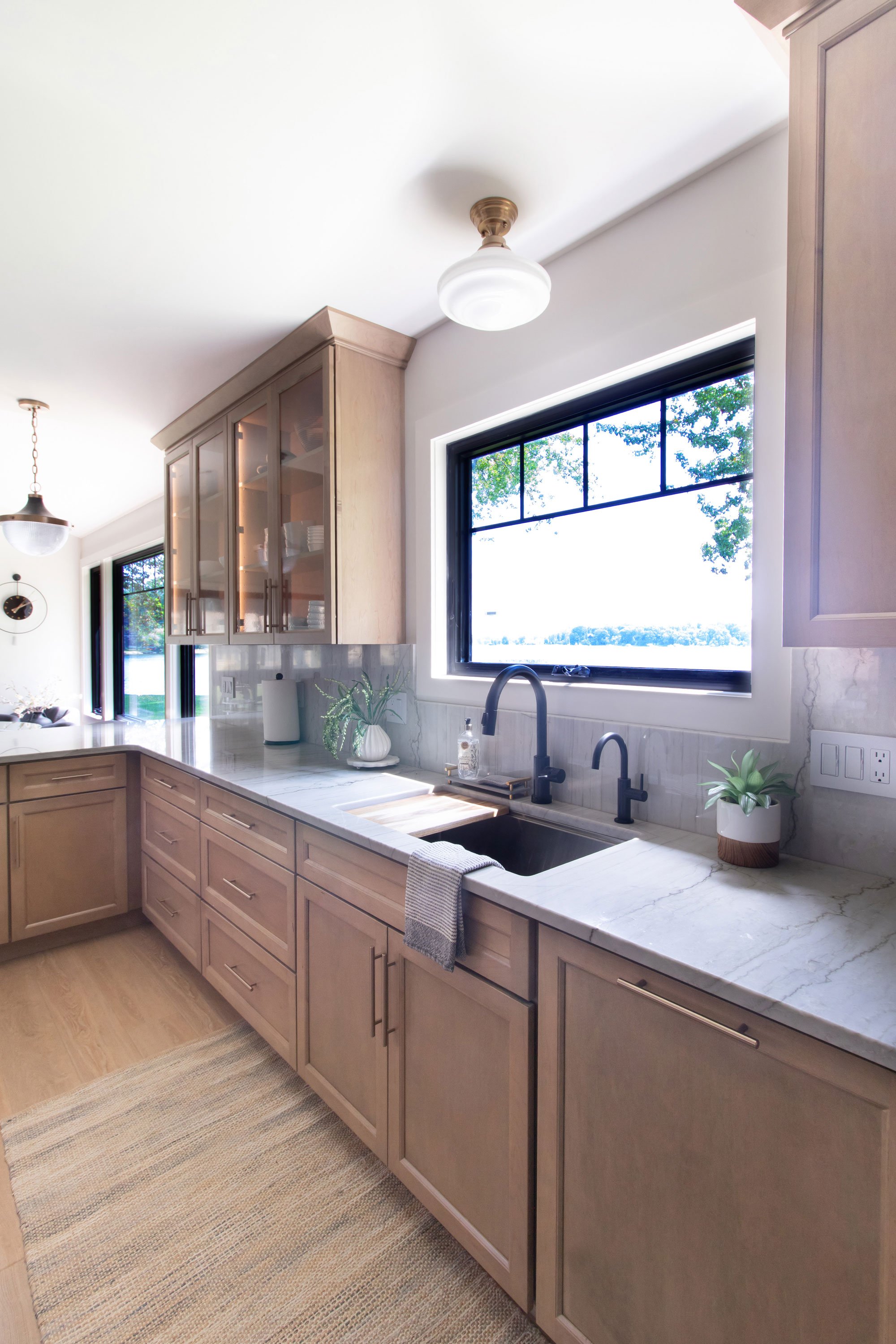 Kitchen sink area with black fixtures, marble-look backsplash, and a window view of the lake.