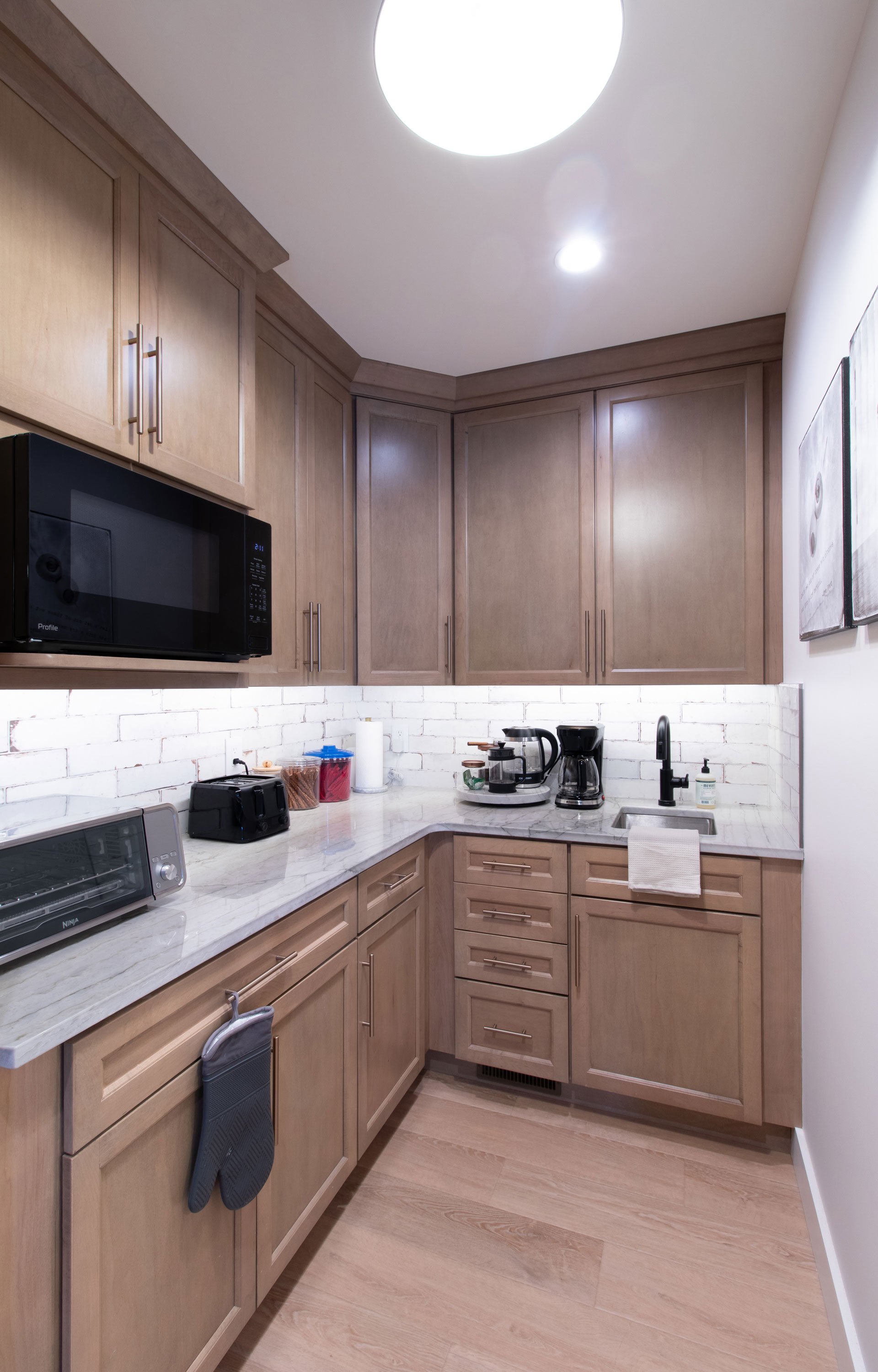 Corner pantry with light wood cabinetry, built-in microwave, and small appliance station.