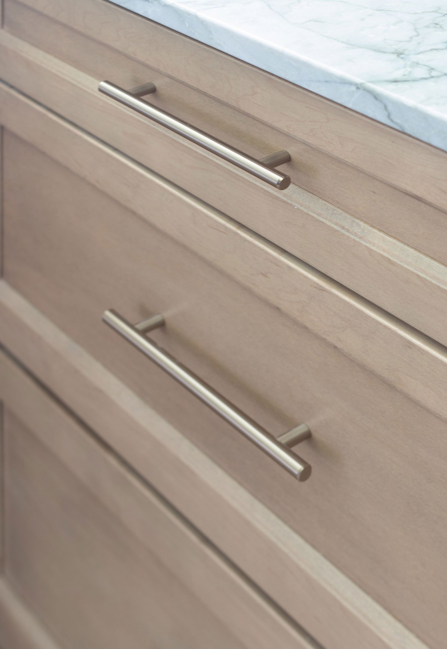 Wicker stained maple cabinetry with gold hardware and light quartz countertop.