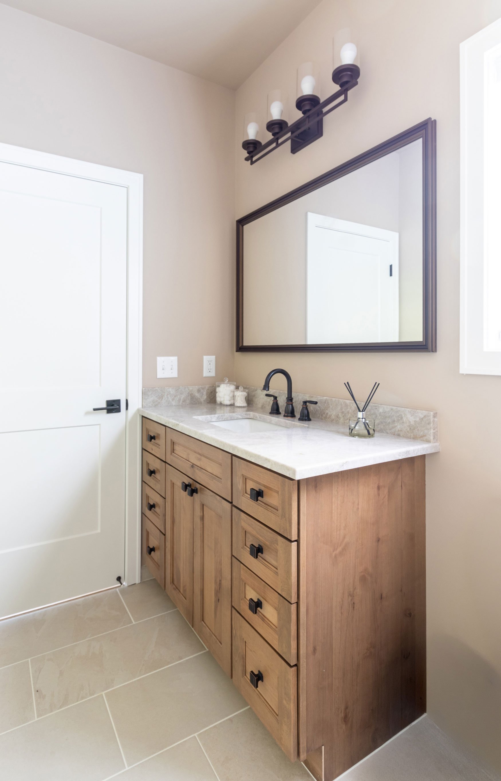 A single vanity in the hallway bathroom featuring Dura cabinetry in a soft Alder stain and oil-rubbed bronze fixtures.