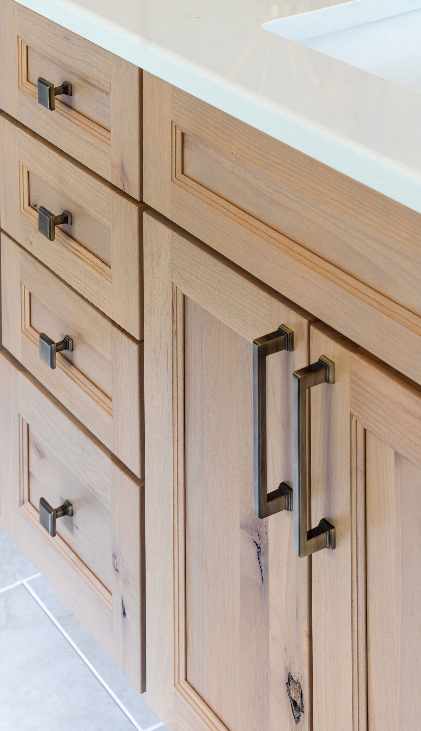 Close-up of alder cabinet drawers and doors with bar-style pulls.