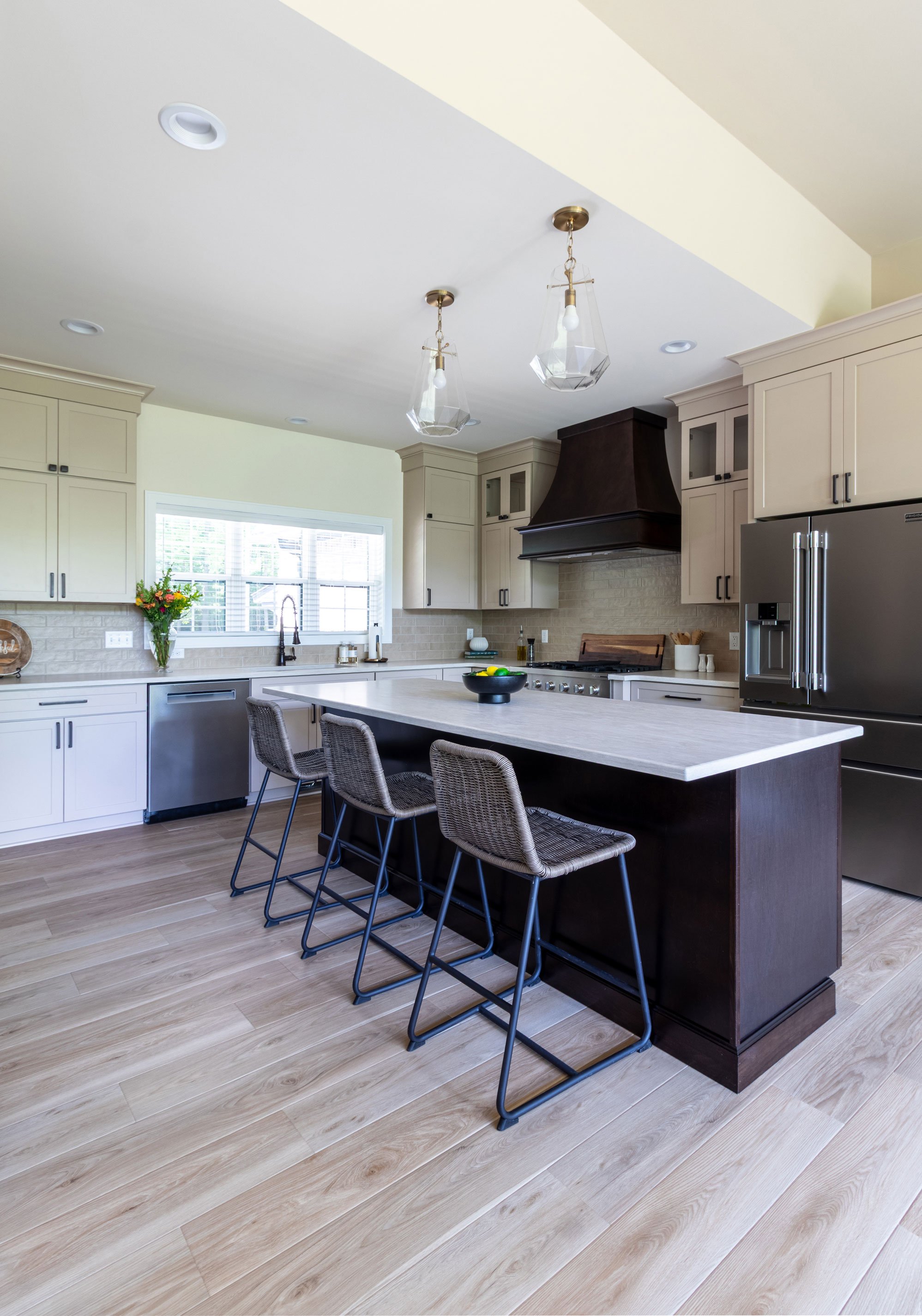 The kitchen island and seating area, showing woven counter stools, the Maple Peppercorn island, and stainless refrigerator.