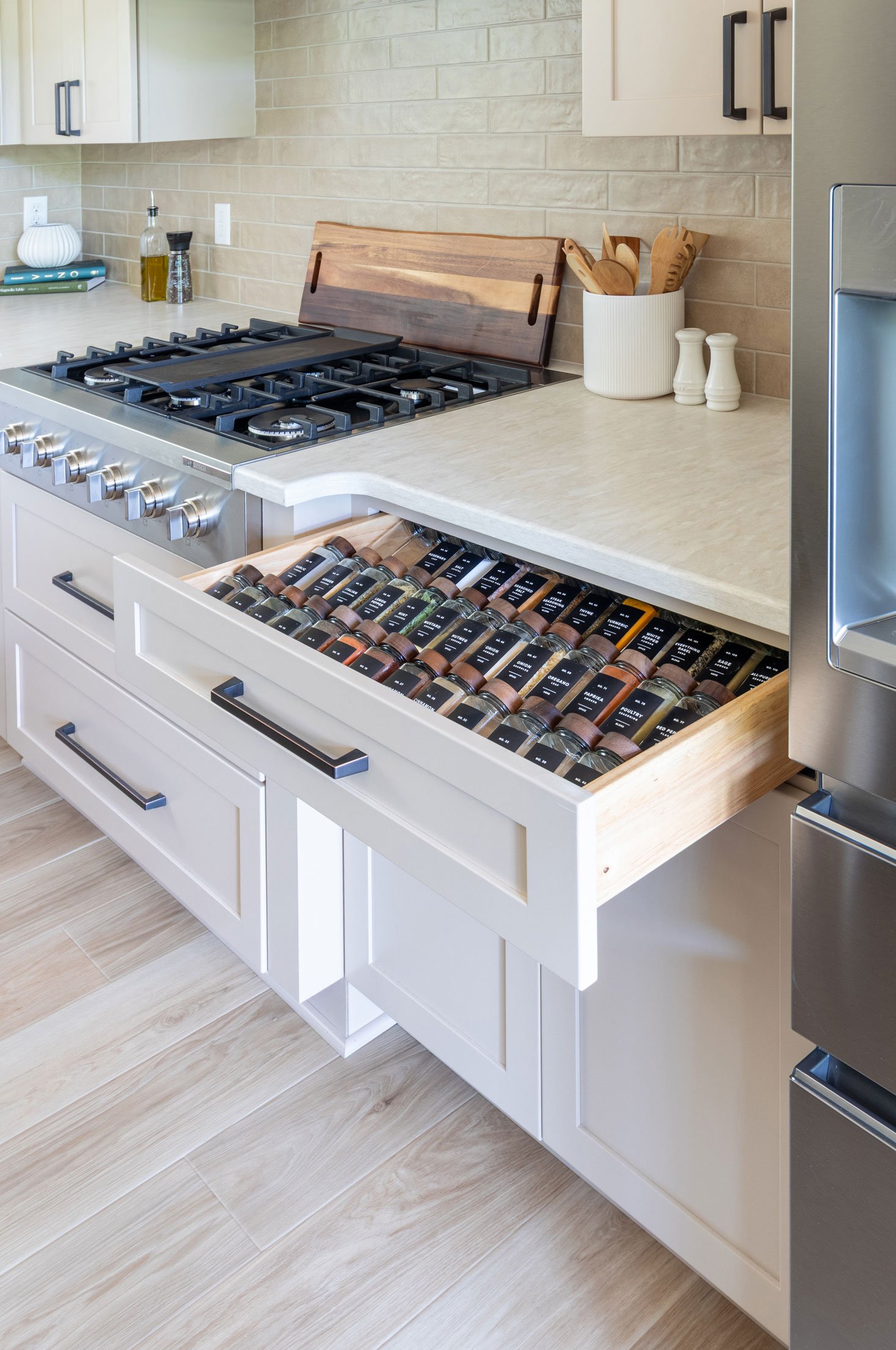 A pull-out spice drawer with rows of labeled jars beside the cooktop.