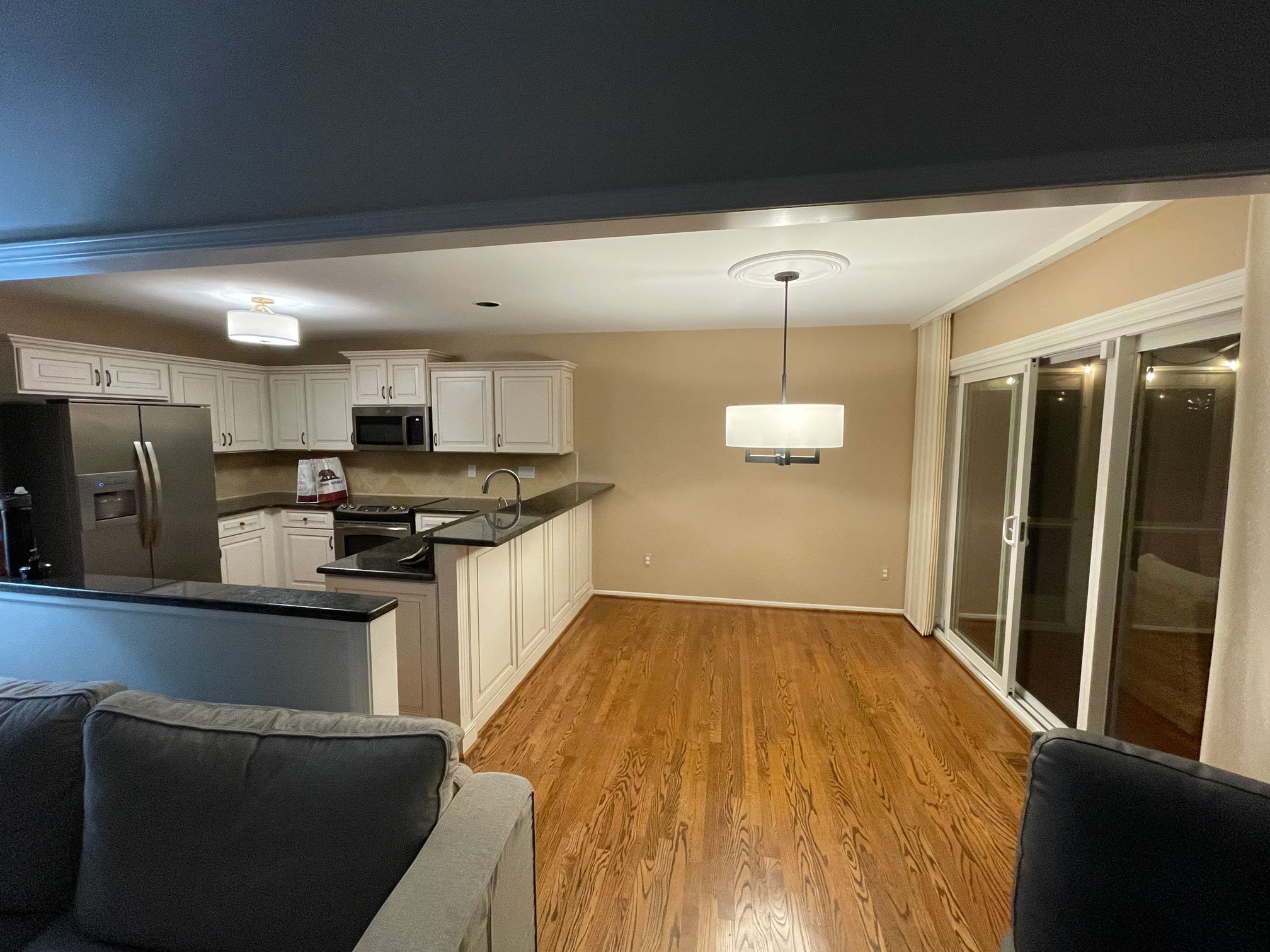 Original kitchen with raised peninsula, dark granite countertops, white cabinetry, and adjacent dining area.