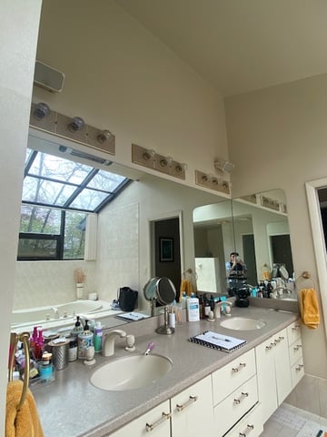 Long double sink vanity with cluttered countertop and limited storage