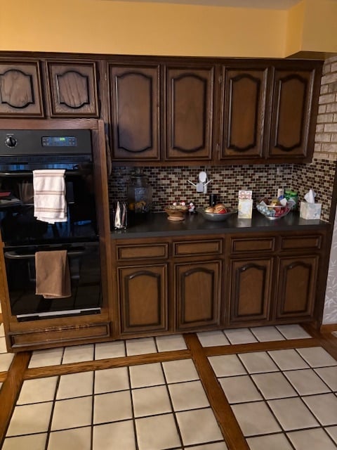 The original 1970s kitchen, featuring dark wood cabinetry, a black built-in wall oven, and checkerboard tile flooring with a wood grid inlay before the remodel.