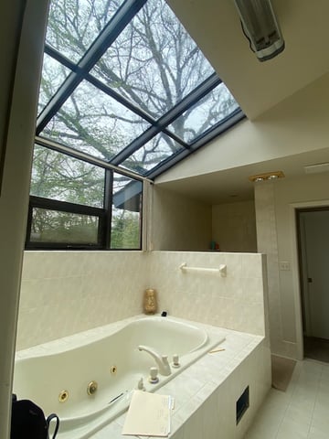 Built-in bathtub under skylight with cream tile surround