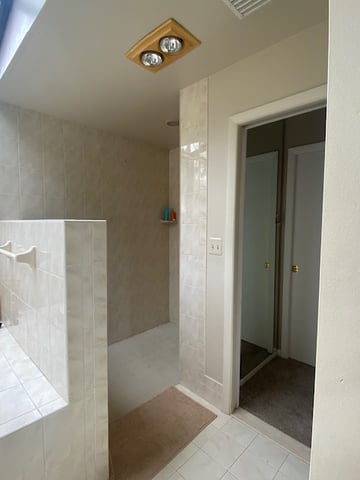 Walk-in shower with half wall and outdated cream tile