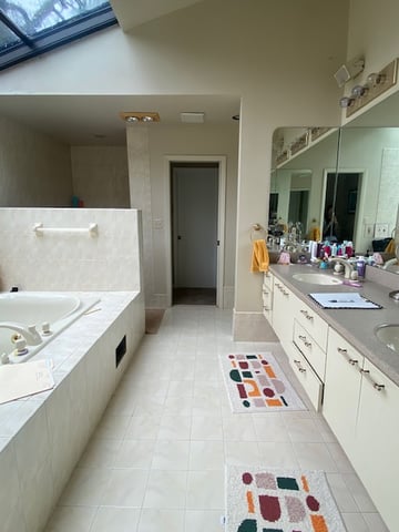 Dated master bathroom with large skylight and built-in tub platform